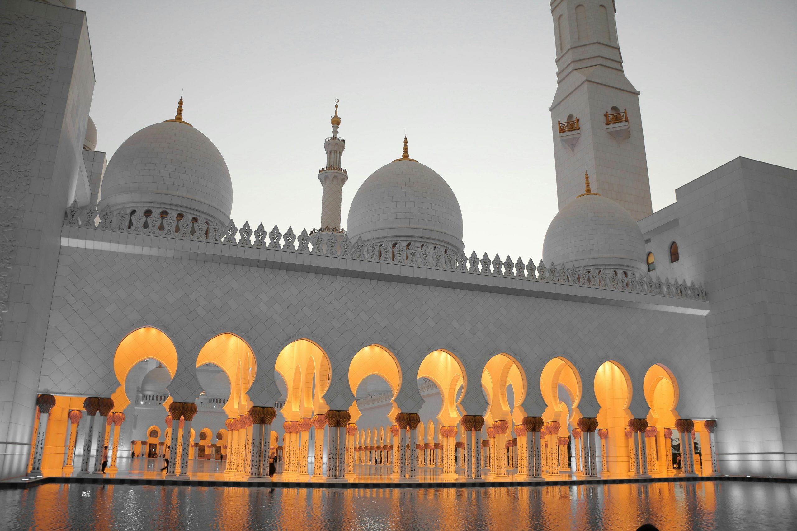 Stunning view of Sheikh Zayed Mosque with illuminated arches and domes during dusk.